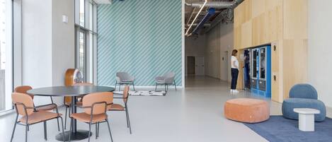 Un interior moderno con una mesa redonda y sillas, un muro con estampado azul y blanco, y una alfombra azul y blanca.