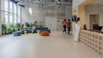 Eine geräumige Lobby mit Sitzbereichen, einem Empfangsbereich und einem großen Fenster, das für natürliches Licht sorgt.