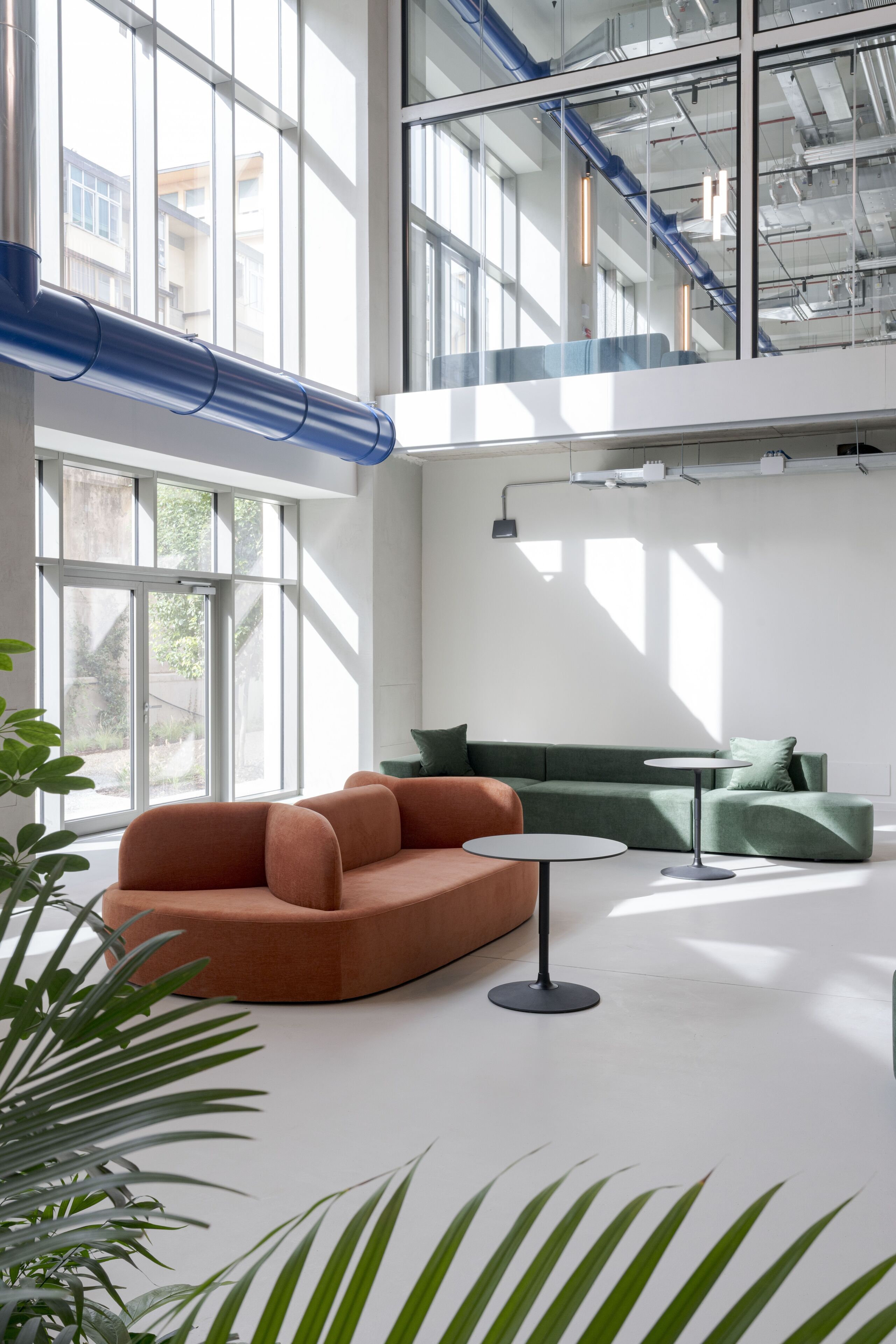 Un interior moderno con un sofá verde, un sillón naranja y una pequeña mesa.