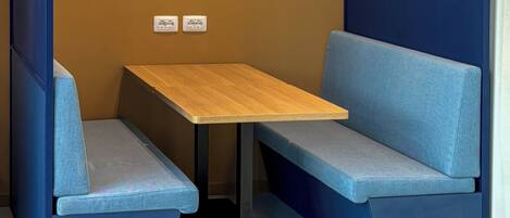 A corner seating area with a wooden table and blue cushioned benches.