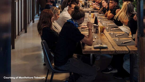 A restaurant with a long communal table, surrounded by patrons. - aparto Florence Manifattura (Florence)