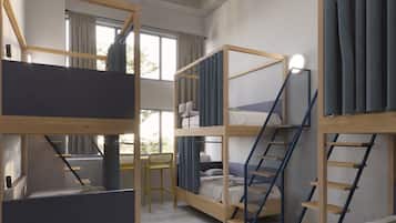 A dormitory room with bunk beds, a desk, and a chair.