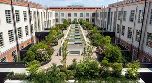 A courtyard with a central garden, surrounded by buildings with large windows and a tiled roof. - aparto Florence Manifattura (Florence)