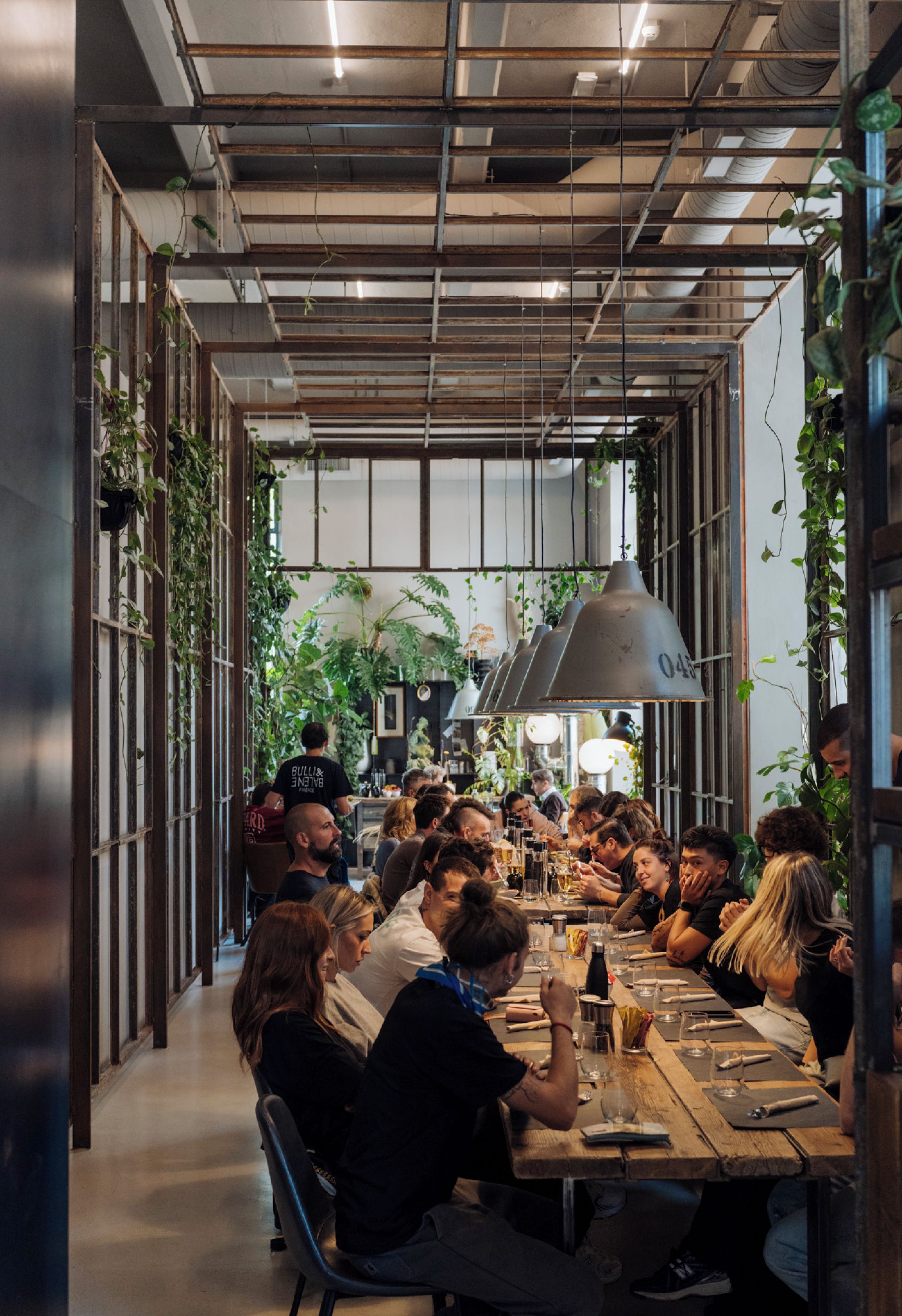 Un restaurant doté d’une longue table commune, autour de laquelle sont assis les clients.