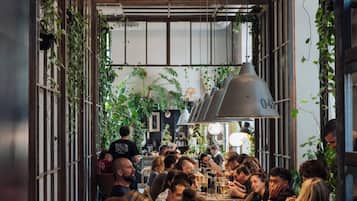 Un restaurante con una mesa larga compartida, rodeado de comensales.
