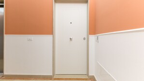 A hallway with a white door, beige walls, and a tiled floor.