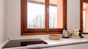 Una cocina con placa de inducción integrada, cafetera y una cesta tejida en la encimera.