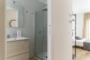 A modern bathroom with a glass-enclosed shower, a white sink with wooden drawers, and a mirror above. - Palazzo Murat - Apartment with city view by Wonderful Italy (Bari)
