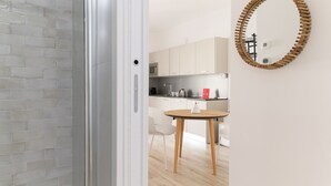A modern kitchen with white cabinets, a microwave, and a coffee machine.