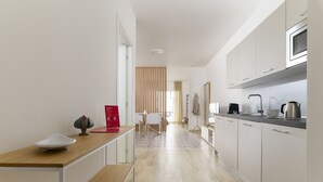 A modern kitchen with white cabinets, a wooden countertop, and a dining area with a table and chairs.