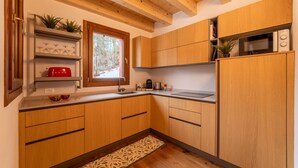 A modern kitchen with wooden cabinets, a built-in microwave, and a window with a view of trees.