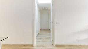 Ein Flur mit Oberlicht, weißen Wänden und Holzboden.