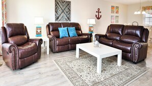 A living room with two brown leather sofas, a white coffee table, and a patterned rug. - Oceanfront 3 BR Condo with Shared Pool! Admiral's Quarters II 13 (Surfside Beach)