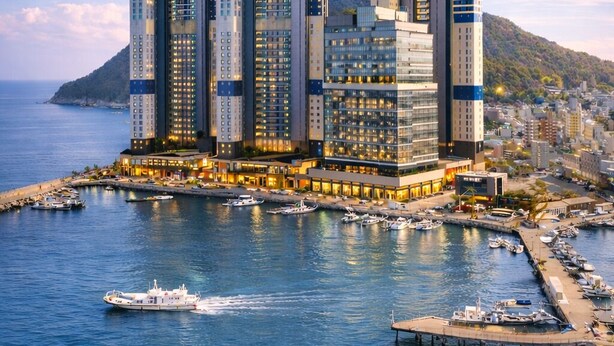 Un hotel moderno de gran altura con varios pisos, ubicado junto a un muelle con barcos amarrados.