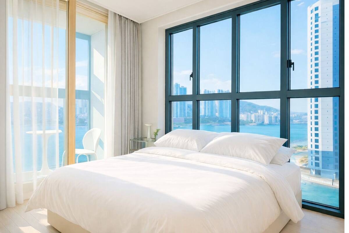 Un dormitorio amplio con una cama grande, una puerta de cristal que da a un balcón y vistas a la ciudad.
