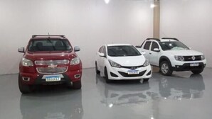 Three cars parked in a clean, well-lit indoor space with a high ceiling and plain walls. - HOTEL COLINAS (Varzea Grande)