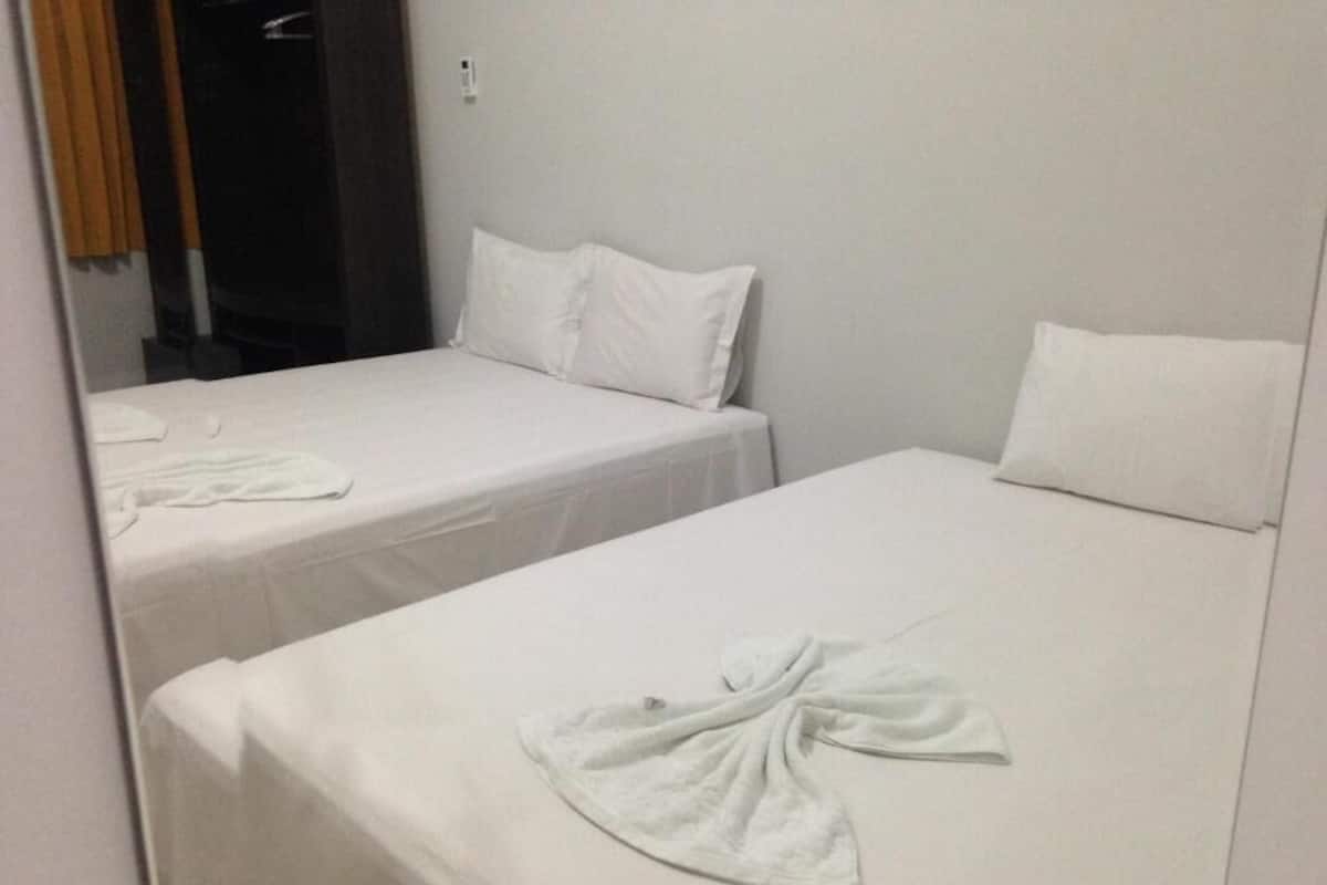 Two single beds with white linens and towels arranged on them.