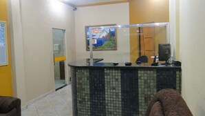 A reception area with a tiled counter, a framed picture on the wall, and a glass door leading to a bathroom. - HOTEL COLINAS (Varzea Grande)