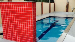 A swimming pool with a red tiled wall and a clear blue water surface. - HOTEL COLINAS (Varzea Grande)