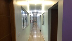 A long, well-lit hallway with doors on both sides, leading to various rooms. - HOTEL COLINAS (Varzea Grande)