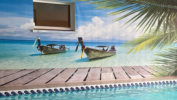 A swimming pool with a tropical mural, wooden deck, and tiled edge. - VILLA, INDOOR POOL, NEAR SAINT-ÉMILION/ BORDEAUX, IDEAL FOR FAMILY. (Puynormand)