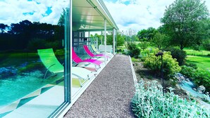 A modern house with a glass exterior, a gravel pathway, and a garden with a stream. - VILLA, INDOOR POOL, NEAR SAINT-ÉMILION/ BORDEAUX, IDEAL FOR FAMILY. (Puynormand)