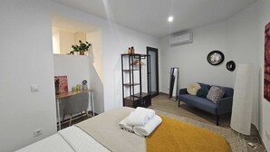 A modern bedroom with a bed, a sofa, a mirror, and a wardrobe. - The Gabriels Chamberi (Madrid)