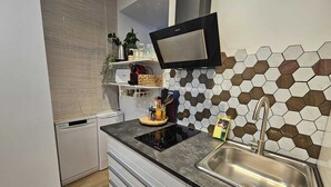 A modern kitchen with a black countertop, stainless steel sink, and a hexagonal tile backsplash. - The Gabriels Chamberi (Madrid)