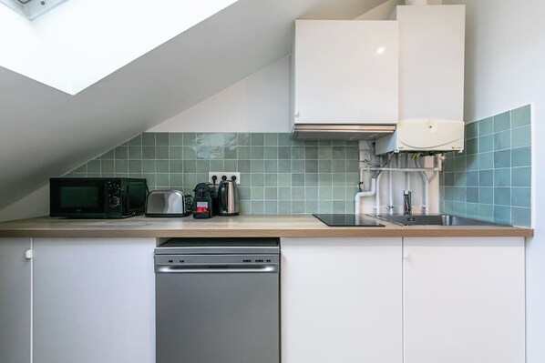 A compact kitchen with a microwave, toaster, coffee maker, and dishwasher.