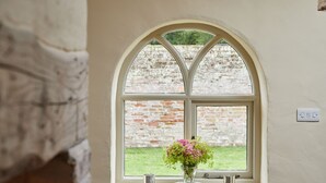 A window with a white frame and a view of a brick wall outside. - Stunning, dog friendly 3 bedroom/3 bathroom cottage close to beaches & short stroll to pub (Banningham)