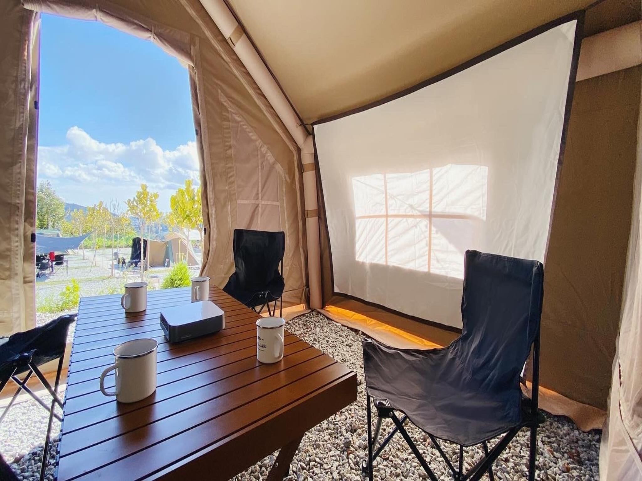 Una carpa con una mesa de madera, dos sillas y un ventanal.