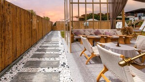An outdoor seating area with wicker furniture and a glass enclosure.