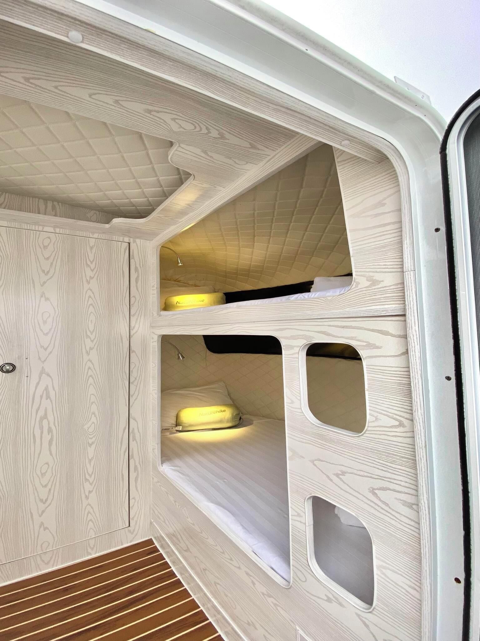Interior de una furgoneta con una cama litera, una mesita y un banco.