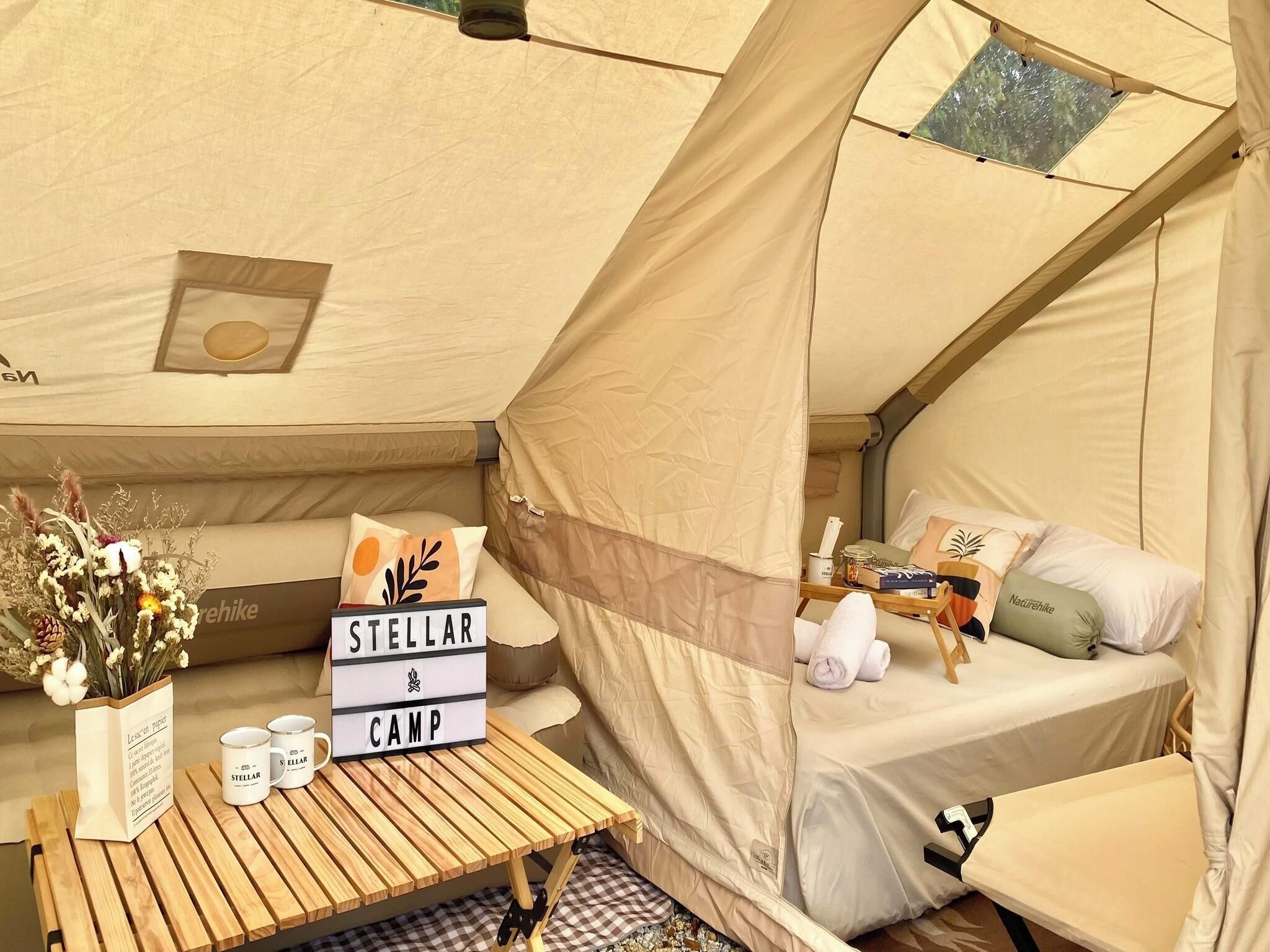 A cozy tent with a bed, a table with a sign, and a window.