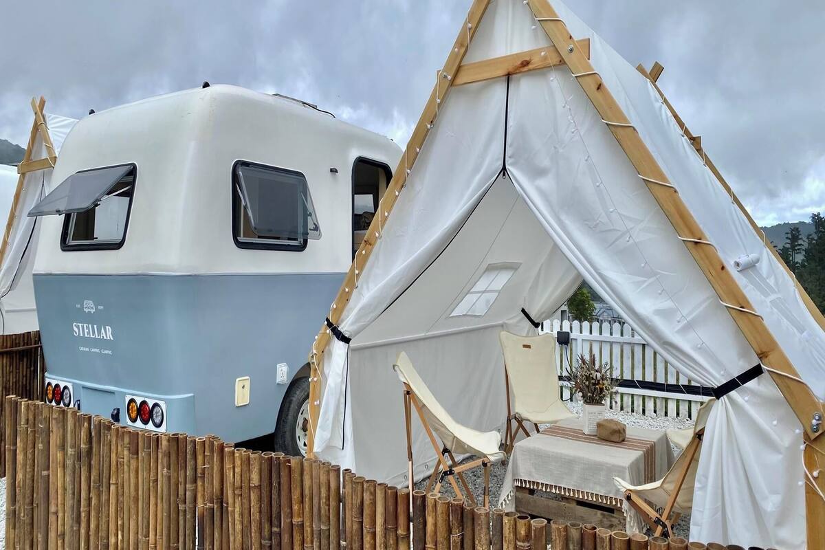 A Stellarl caravan and a tent set up in a campsite.