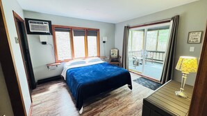 Ein Schlafzimmer mit einem Bett, einem Schreibtisch, einem Stuhl, einem Fenster und einem Balkon.