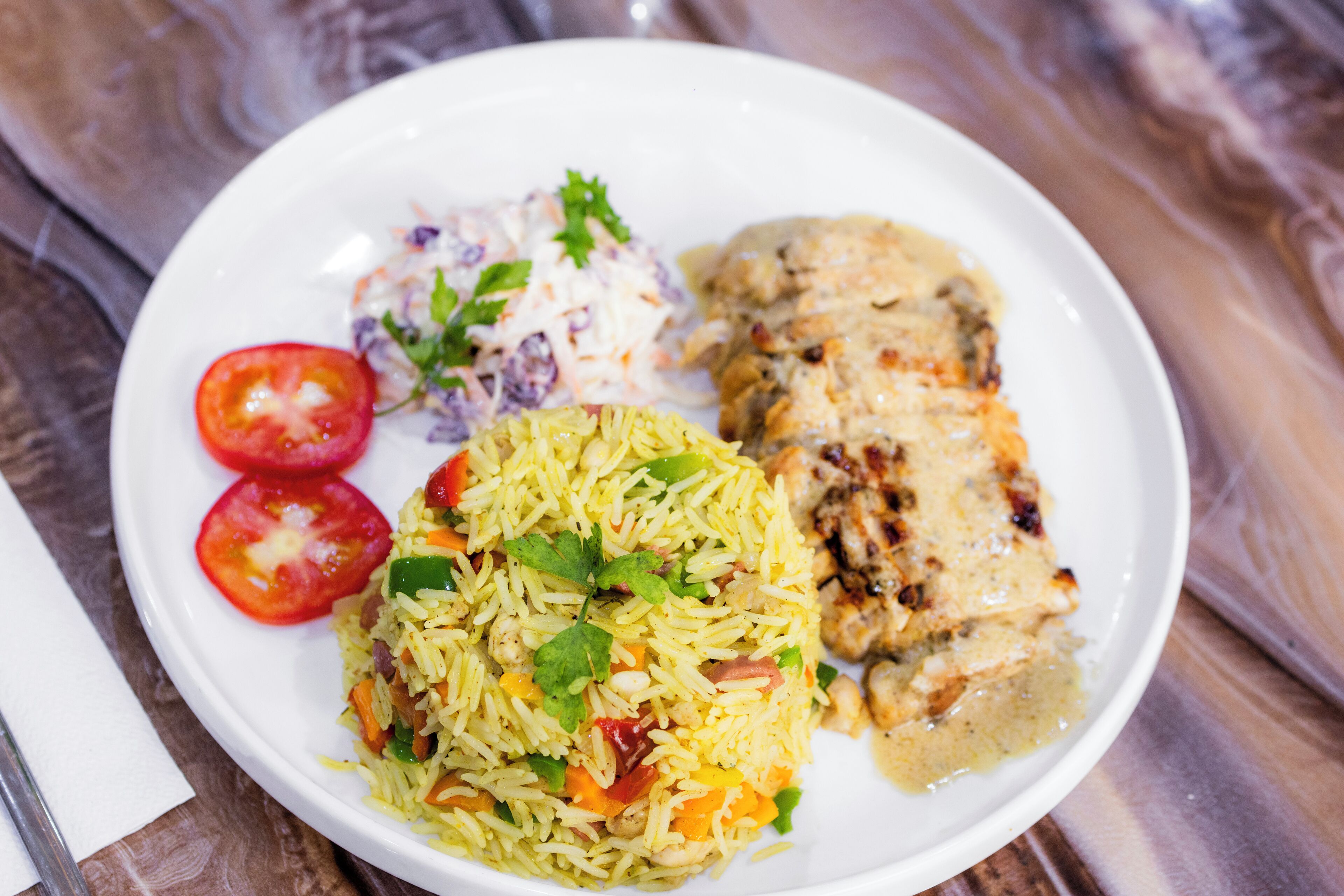Ein Teller Essen mit Reis, Hähnchen und einem Beilagensalat.