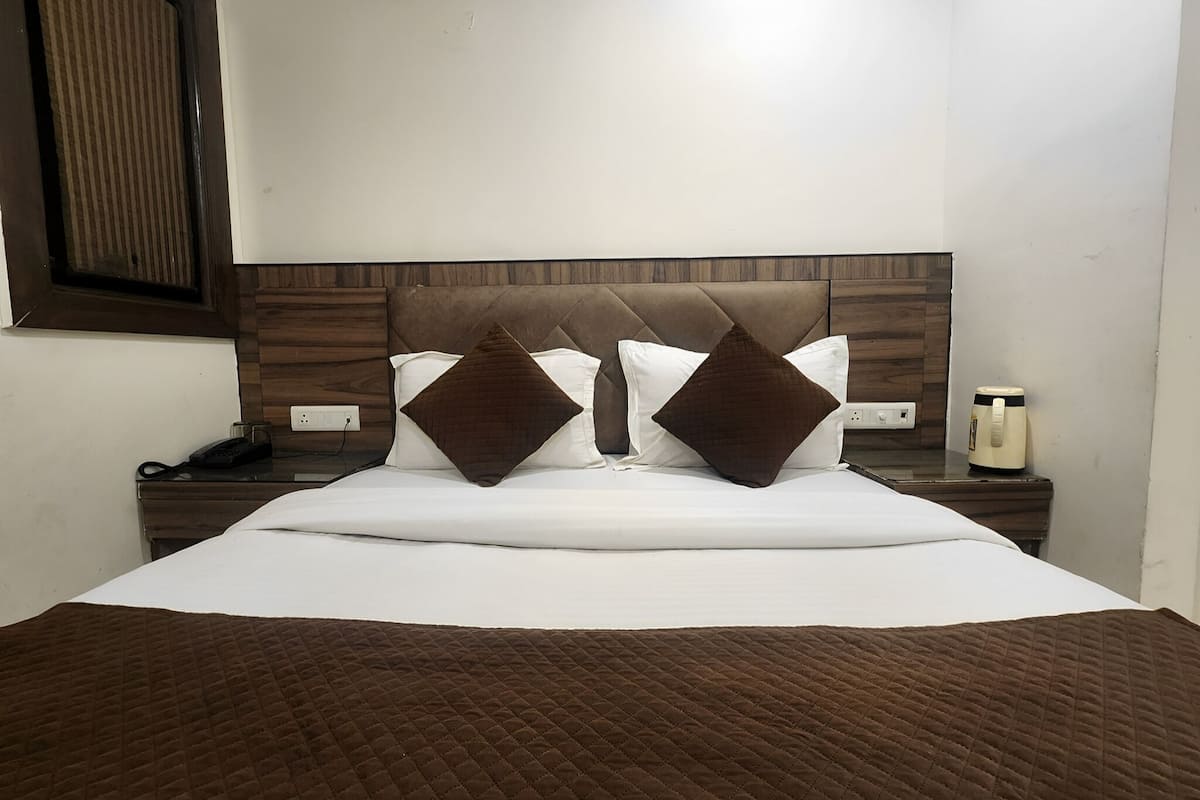A neatly made bed with a brown quilt, two brown pillows, and a wooden headboard.