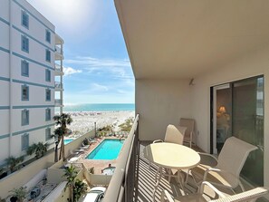A balcony with a view of a beach and a swimming pool.