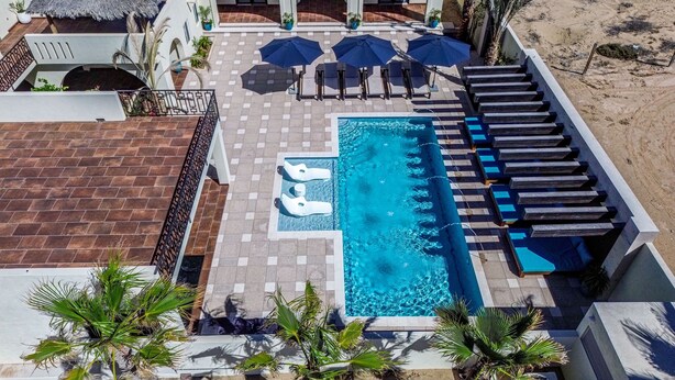 A rooftop pool area with a swimming pool, lounge chairs, and umbrellas.