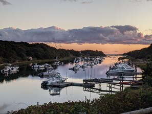 A marina with boats docked, surrounded by greenery and a sunset in the background. - Pet Friendly Waterfront Overlooking Oyster River (Chatham)