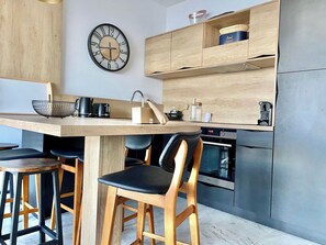 Una cucina moderna con isola in legno, sgabelli da bar, orologio a parete ed elettrodomestici integrati.