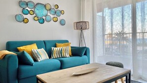 A teal sofa with patterned cushions, a wooden coffee table, and a wall art piece. - 55-"Le rêve éveillé", vue mer, garage 38 (Menton)