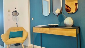 A modern living room with a yellow armchair, a console table with decorative items, and a large mirror on the wall. - 55-"Le rêve éveillé", vue mer, garage 38 (Menton)
