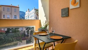 A balcony with a table set for two, featuring yellow chairs and a black tablecloth. - 72-"Charmant studio" Plein centre, Calme, Terrasse (Menton)