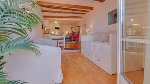 A room with a bed, a sofa, a hanging chair, a dining area, and a kitchen in the background. - 14-"La Belle Vue Mer" Cozy Appartement, Centre, Pl (Menton)