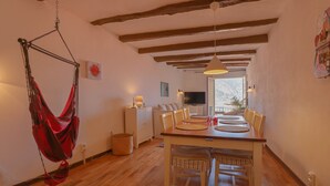 A dining area with a wooden table, chairs, a hanging red hammock, and a view to the outside. - 14-"La Belle Vue Mer" Cozy Appartement, Centre, Pl (Menton)