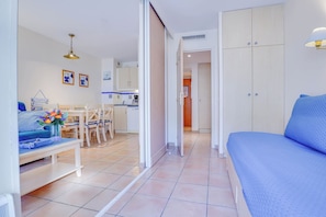 A modern living room with a sofa, a dining table with chairs, a kitchen area, and a wardrobe. - 70-2 pièces plein Centre, Terrasse, Parking (Menton)