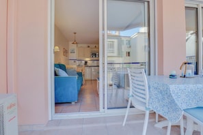 A modern interior with a dining area, a sofa, and a kitchen visible through a glass door. - 70-2 pièces plein Centre, Terrasse, Parking (Menton)