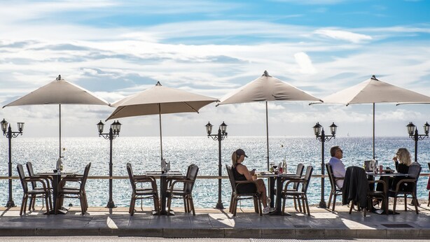 An outdoor dining area with tables and chairs under umbrellas, overlooking a body of water. - 6-"Aux Rivages du Parc" Plein Centre, Calme, Plage (Menton)